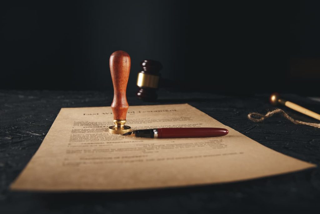 Last will and testament document with notary seal stamp and pen on a dark table, highlighting the importance of legal notarization for estate planning.