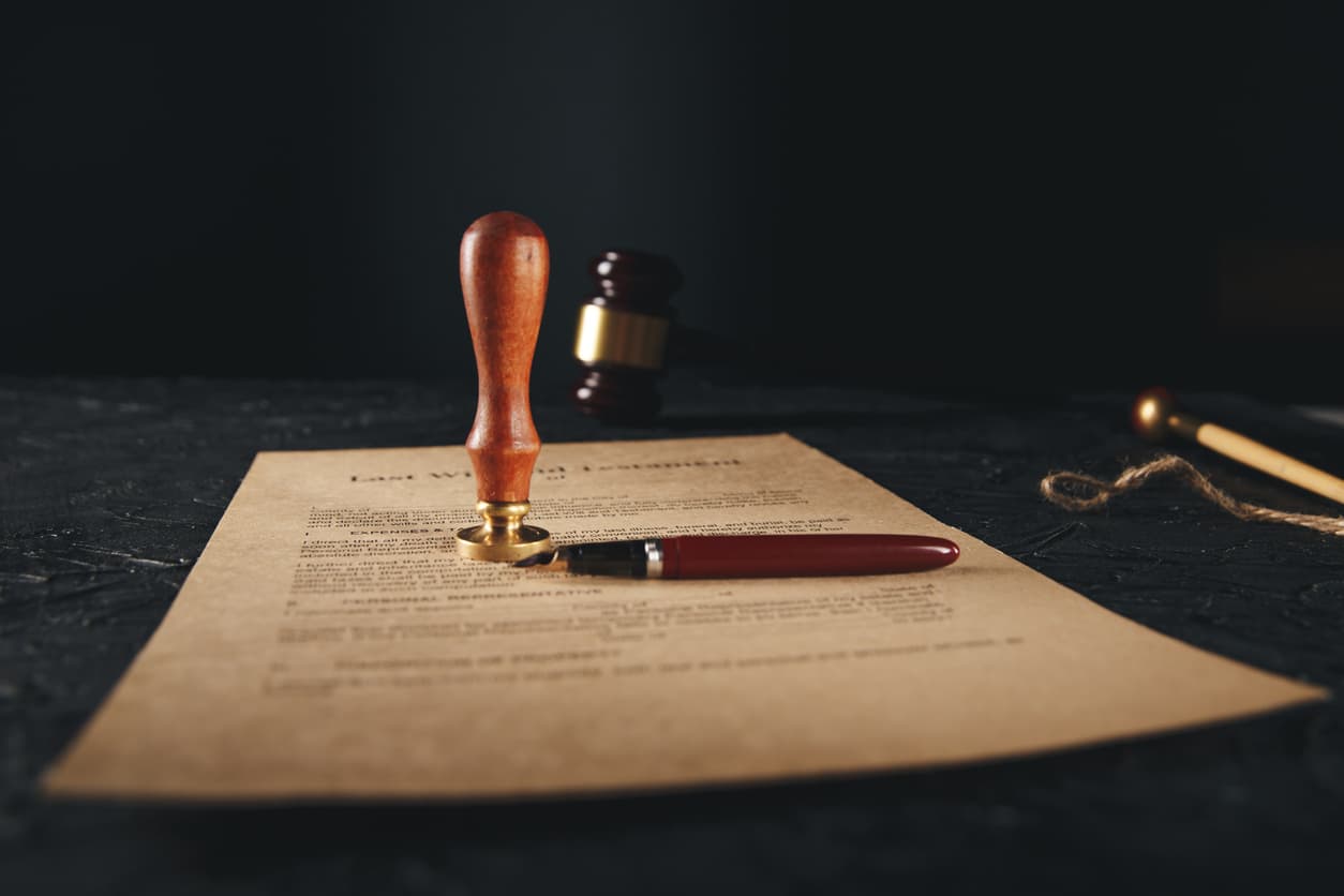 Last will and testament document with notary seal stamp and pen on a dark table, highlighting the importance of legal notarization for estate planning.