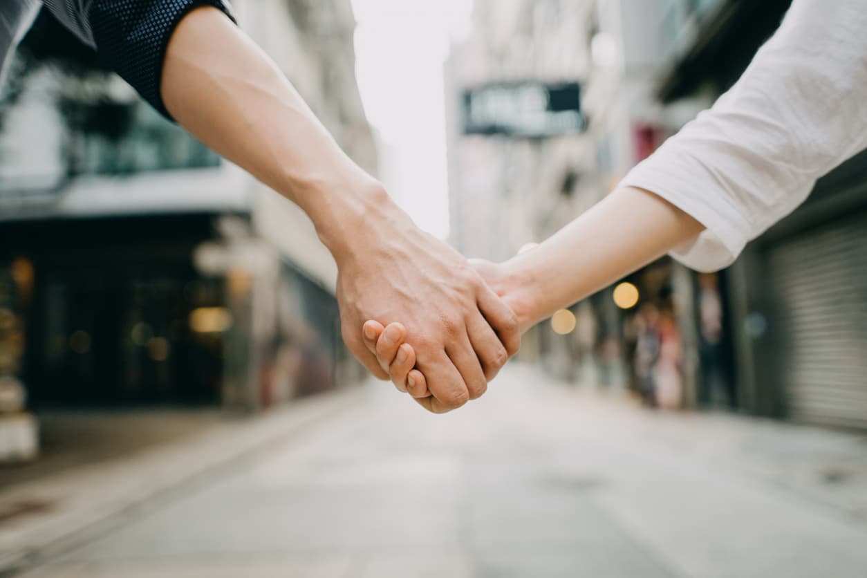 Close-up of a couple holding hands on a city street – symbolizing civil partnership. Learn how to notarize or Apostille your civil partnership certificate with NotaryPublic24.