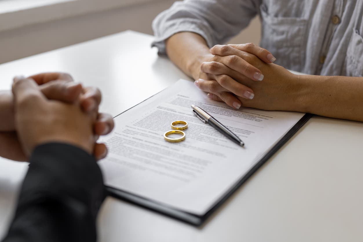 Close-up of two people sitting across a table with a divorce agreement, wedding rings, and a pen in focus — symbolizing the legal separation process involving Decree Nisi and Decree Absolute, relevant for international document legalization and notary services at NotaryPublic24.com